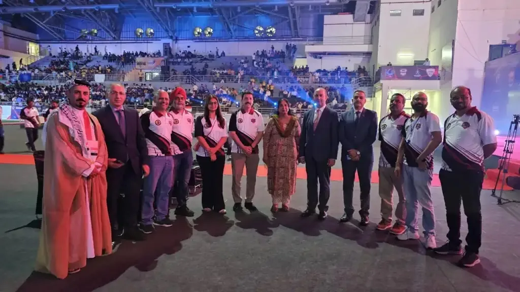 Group photo of Technoxian organisers and officials standing on the arena floor with a packed stadium audience behind them