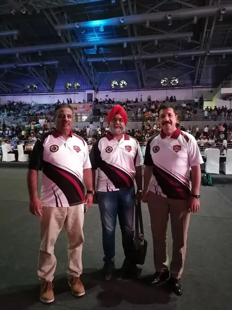 Three men in matching Technoxian polo shirts posing on the arena floor with the stadium crowd in the background