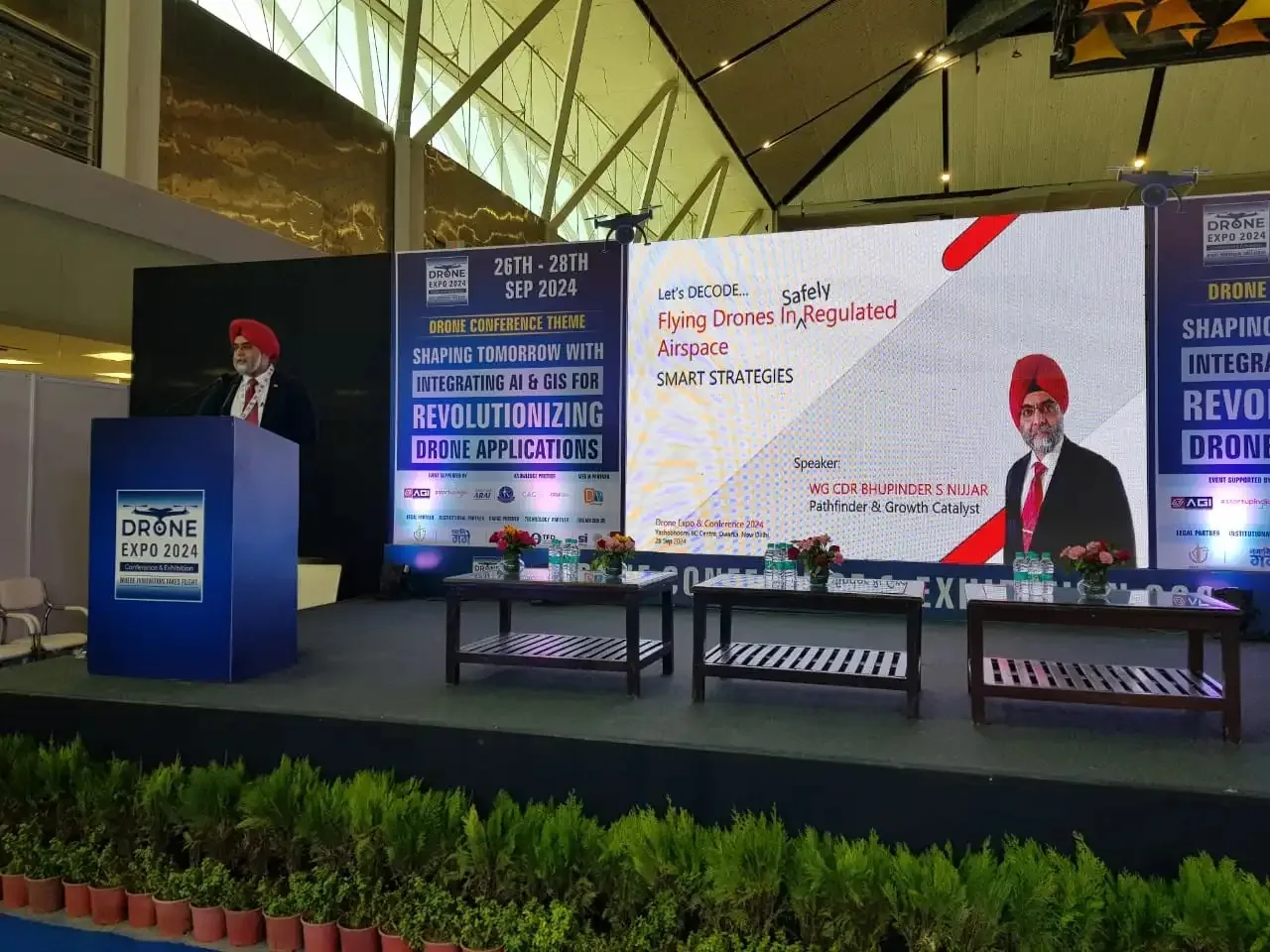 Speaker at the podium at Drone Expo and Conference 2024 with a screen behind announcing his talk on flying drones safely in regulated airspace
