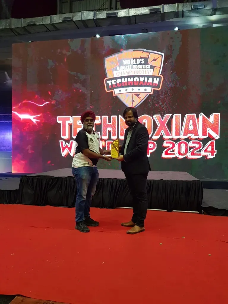 Wide view of the Technoxian World Robotics Championship 2024 trophy presentation on stage with the event logo displayed behind