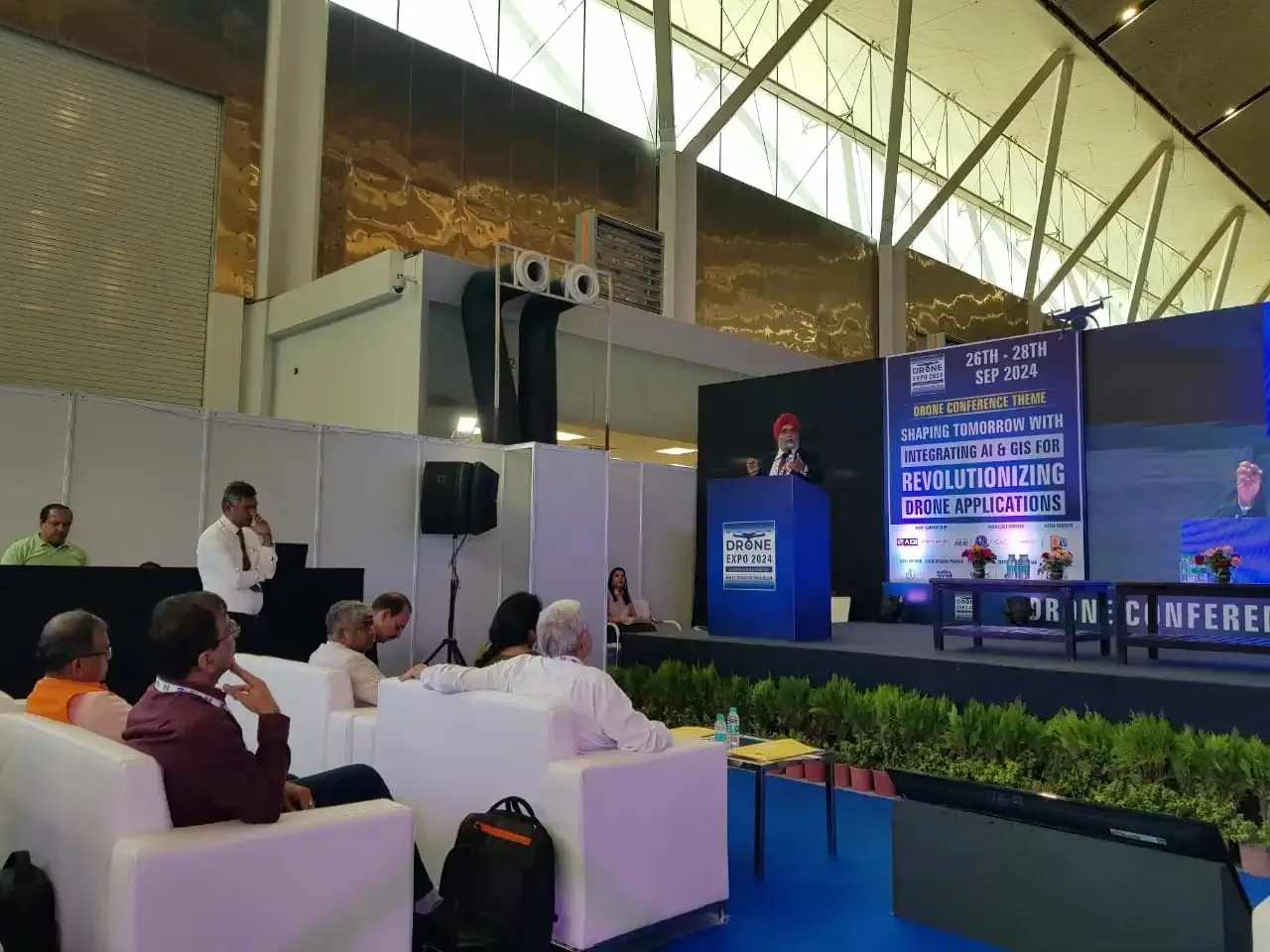 Speaker addressing the audience at Drone Expo 2024, with attendees seated in the foreground and the Drone Conference stage backdrop behind
